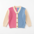 Pink and blue girls knit cardigan with cream sleeves laid flat on white